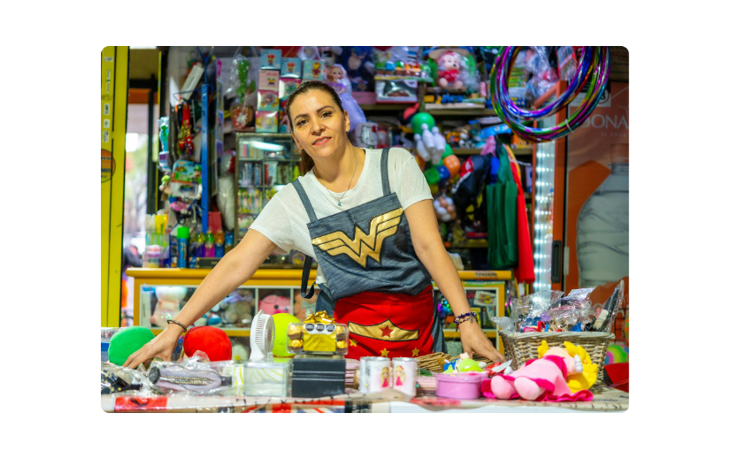 Woman in Wonder Woman shirt behind toy store counter, demonstrating Etsy marketing strategies with diverse products.